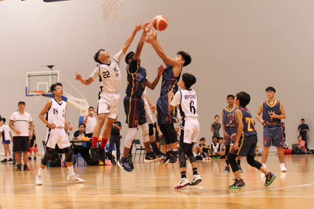 ACS players compete in for a ball in midair against opponents in white.